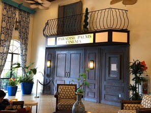 Step into the classic Paradise Palms Cinema, featuring a grand entrance, ornate light fixtures, and a traditional movie-going experience.