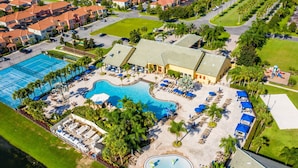An aerial view of a resort with a large swimming pool, multiple lounge areas, and a well-maintained lawn. - Resort Home Sleeps 12 w/private Pool! (Kissimmee)