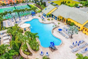 A swimming pool with a slide, surrounded by lounge chairs and umbrellas, with a building in the background. - Resort Home Sleeps 12 w/private Pool! (Kissimmee)