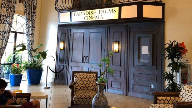 A cinema with a sign reading 'Paradise Palms Cinema,' featuring a balcony with a railing, potted plants, and a seating area with patterned chairs. - Resort Home Sleeps 12 w/private Pool! (Kissimmee)