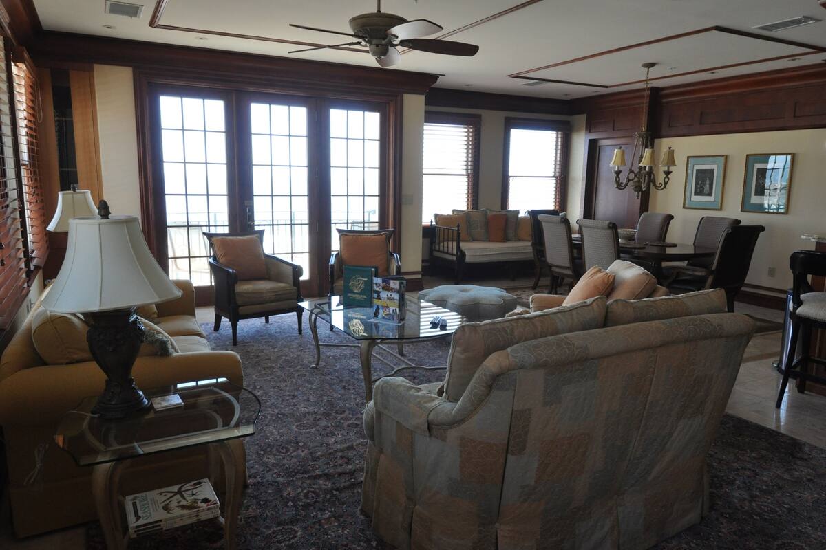 A spacious living room with a large window, a ceiling fan, and a fireplace.