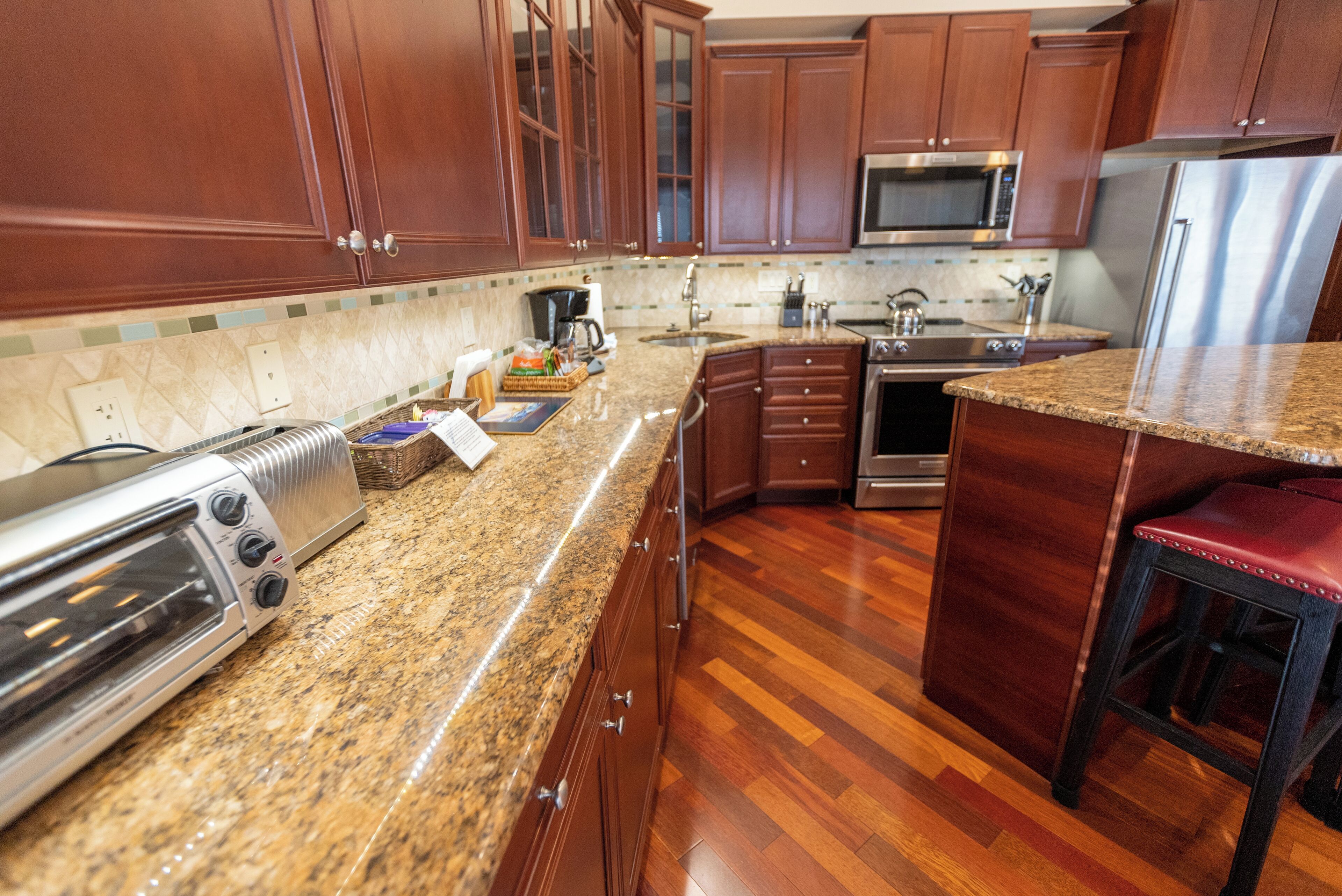 A modern kitchen with granite countertops, stainless steel appliances, and wooden cabinets.