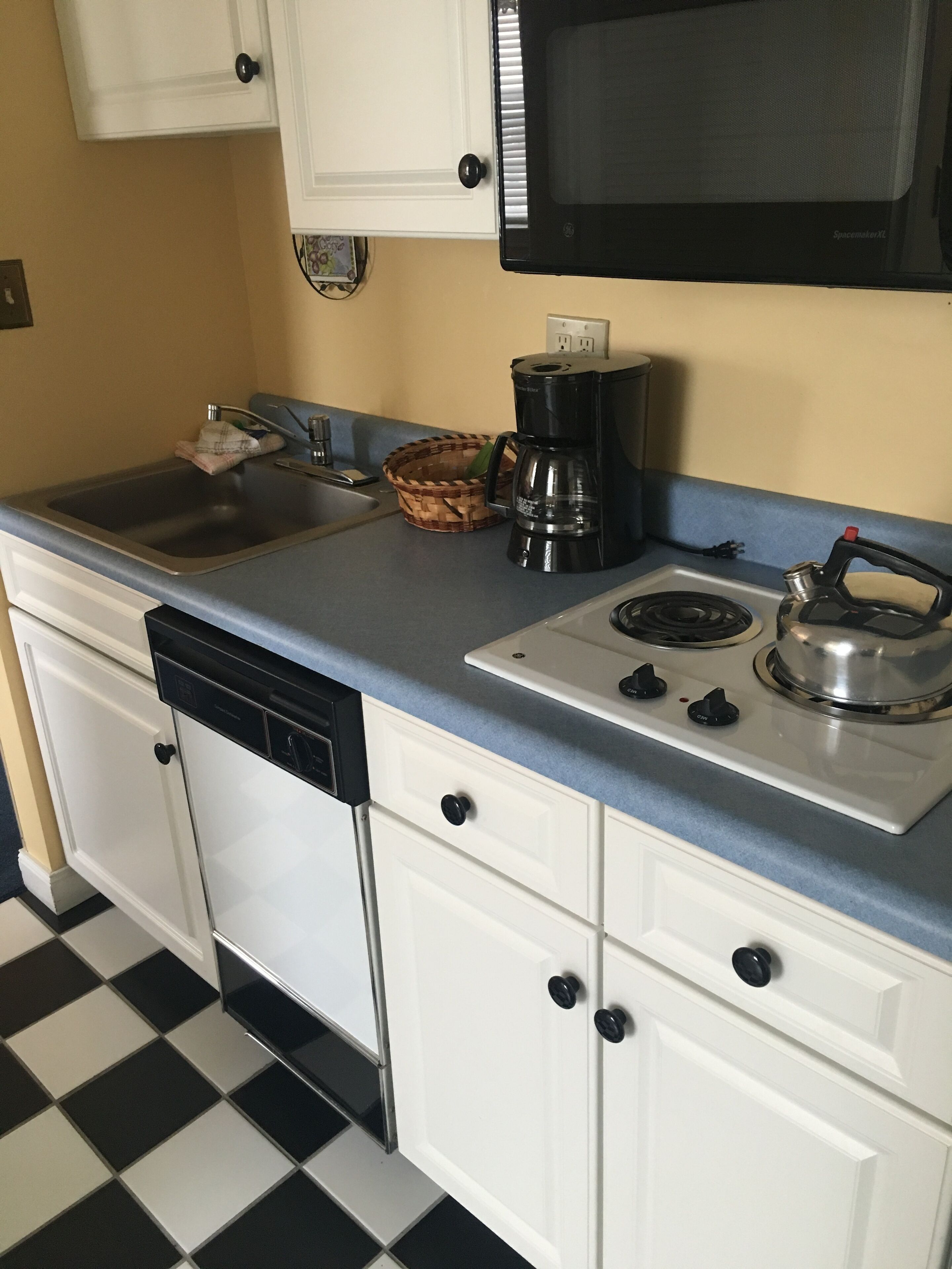 A kitchen with a dishwasher, stove, microwave, and a checkered floor.