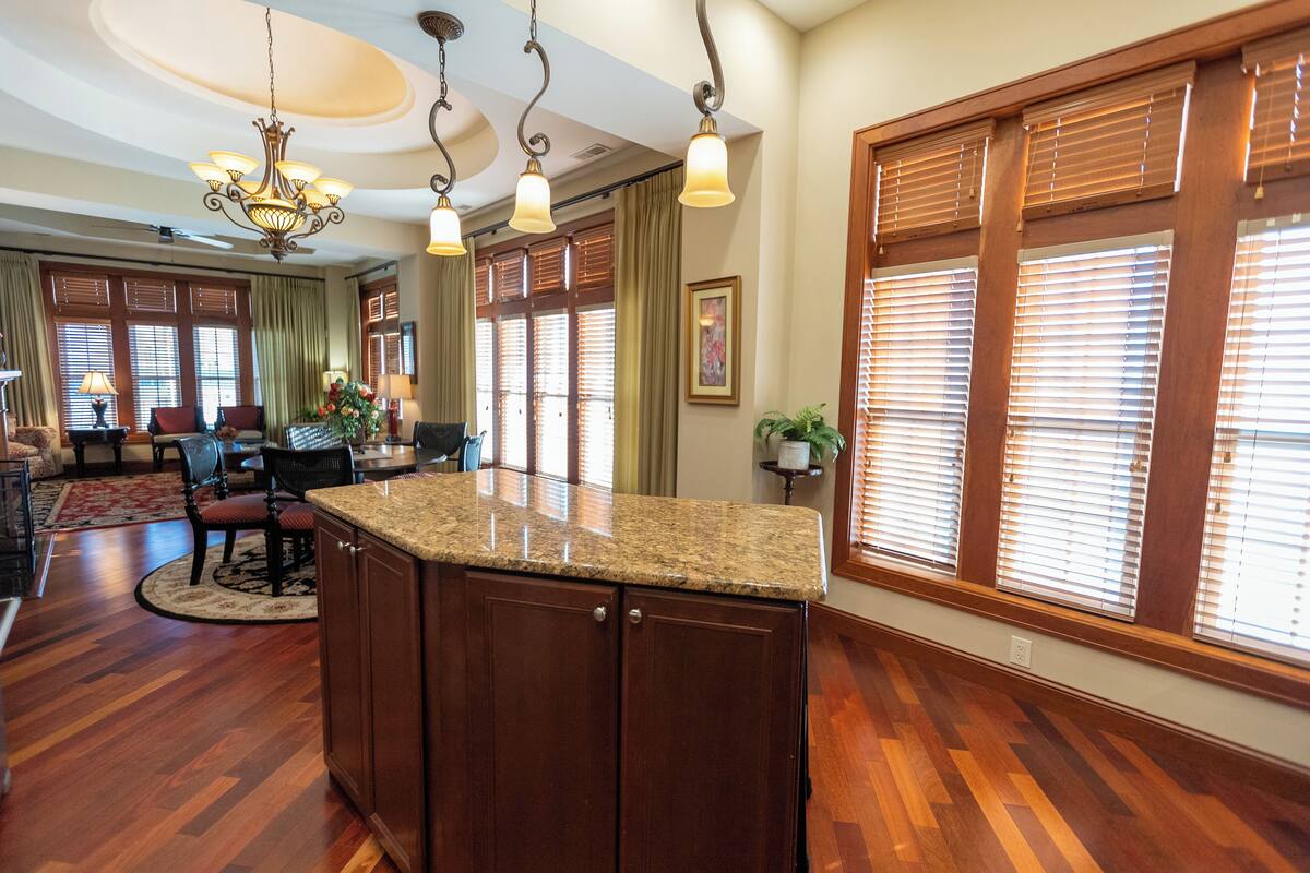 A spacious kitchen with a granite countertop, wooden cabinets, and a chandelier.