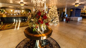 Eine Lobby mit einem runden Tisch in der Mitte, einer Rezeption und einer großen Weihnachtstanne.