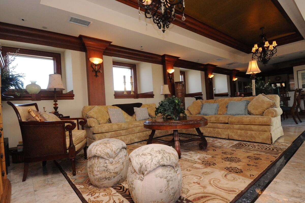 A spacious living room with a large sectional sofa, matching ottomans, a wooden coffee table, and a chandelier.
