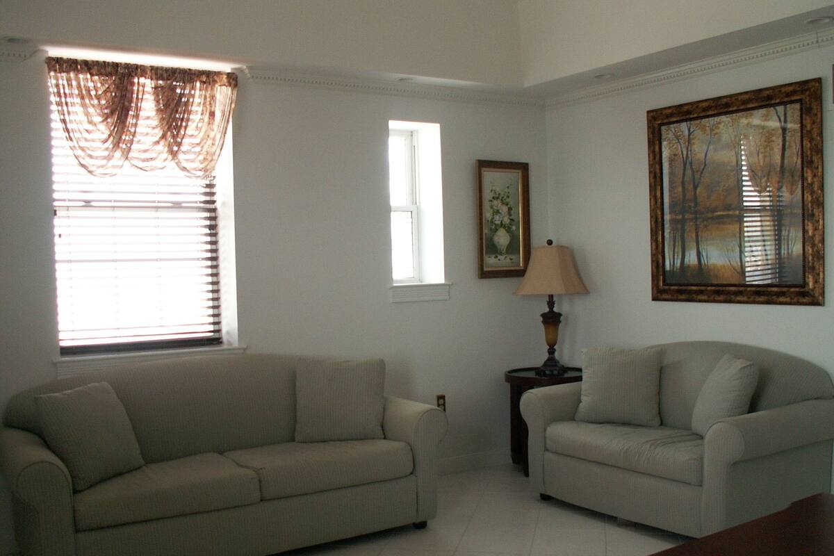 A living room with two sofas, a lamp, and a painting on the wall.