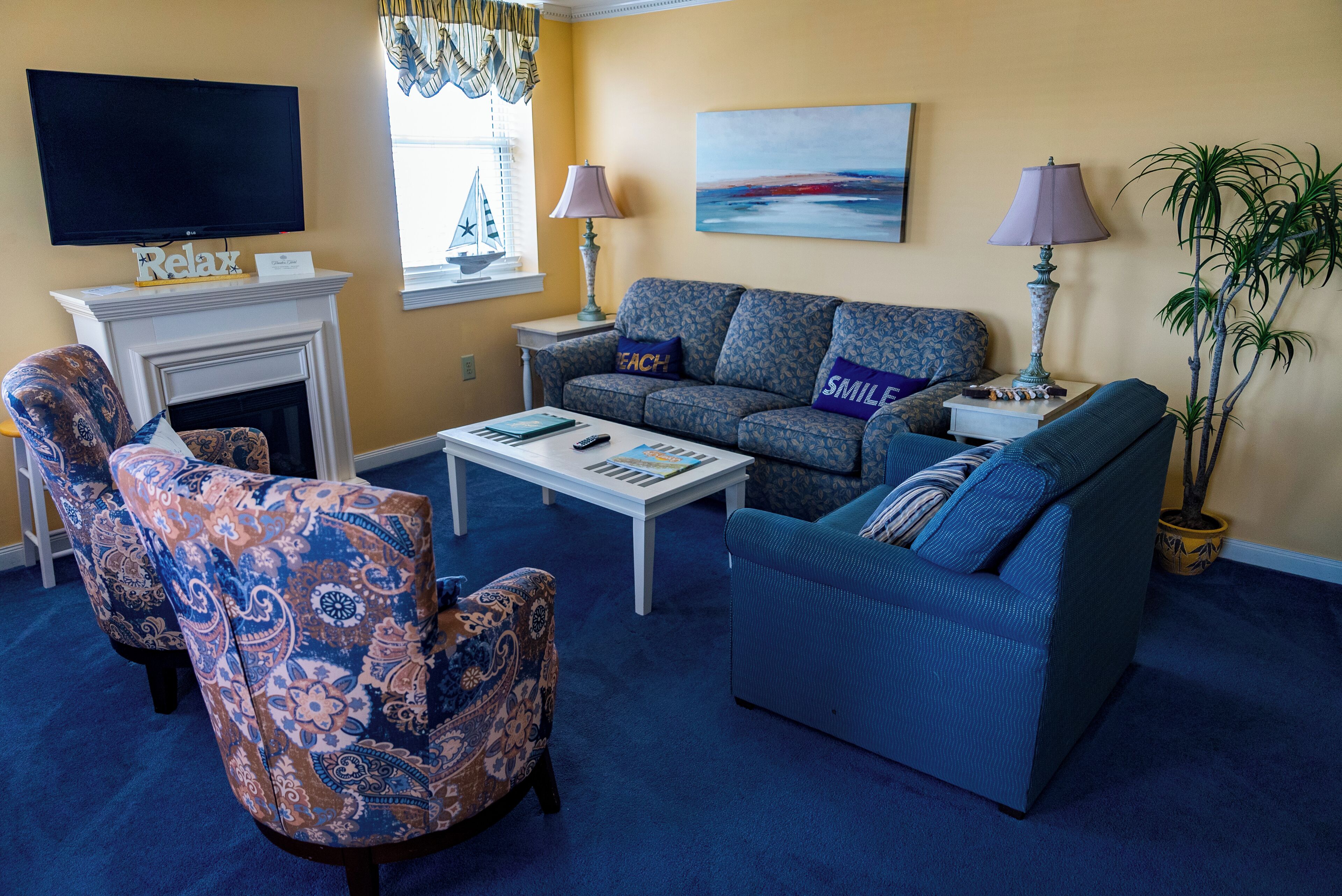 A living room with a fireplace, a sofa, a patterned armchair, a coffee table, and a television.