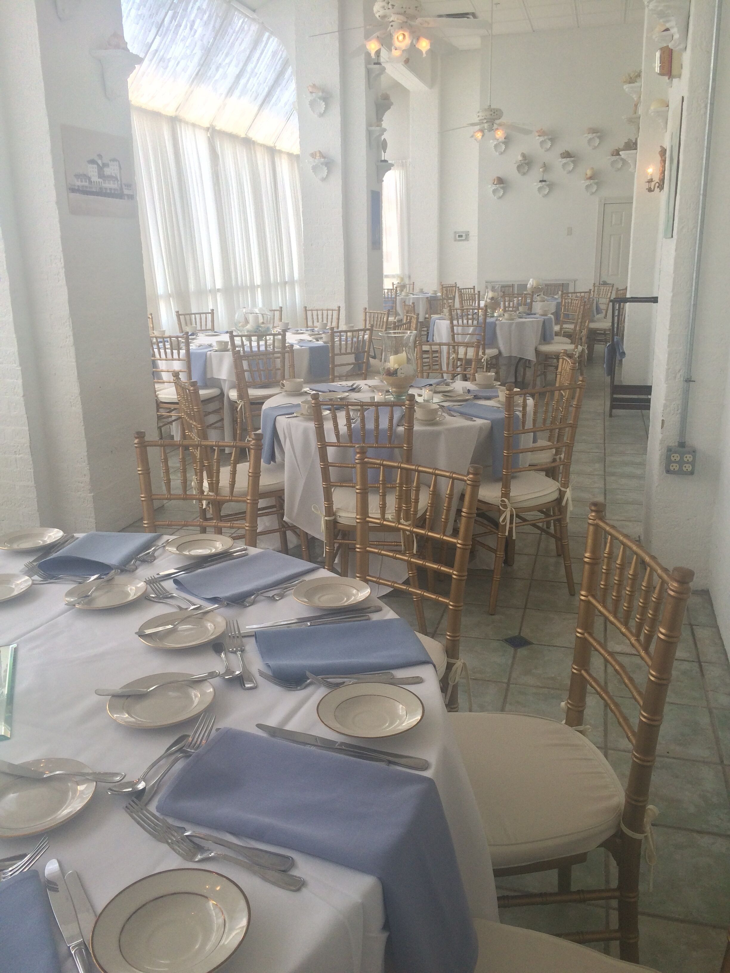 A dining area with tables set for service, featuring white tablecloths and blue napkins.