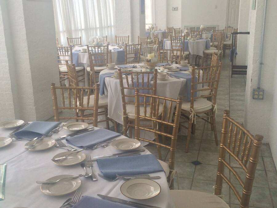 A dining area with tables set for service, featuring white tablecloths and blue napkins.