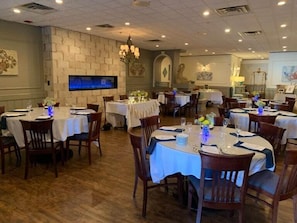 A dining area with round tables, chairs, and a stone wall. - The Flanders Hotel (Ocean City)