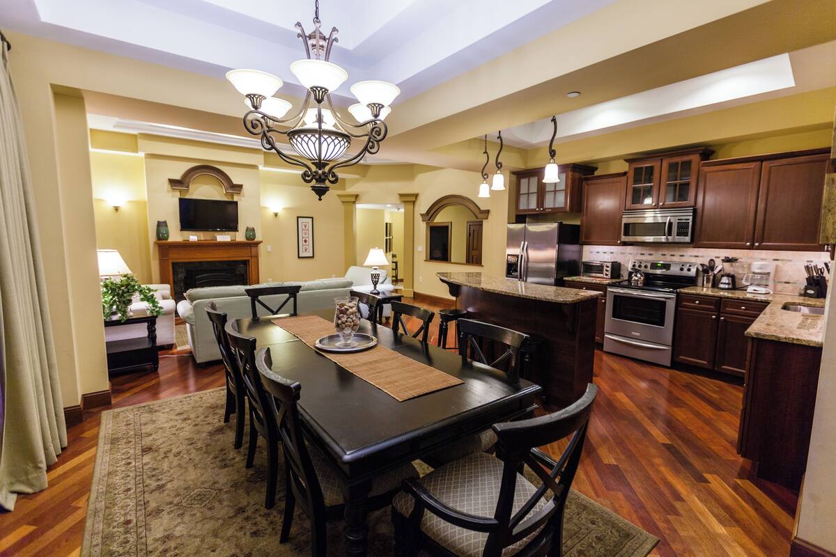 A spacious kitchen with modern appliances, a dining area with a chandelier, and a cozy living room with a fireplace.