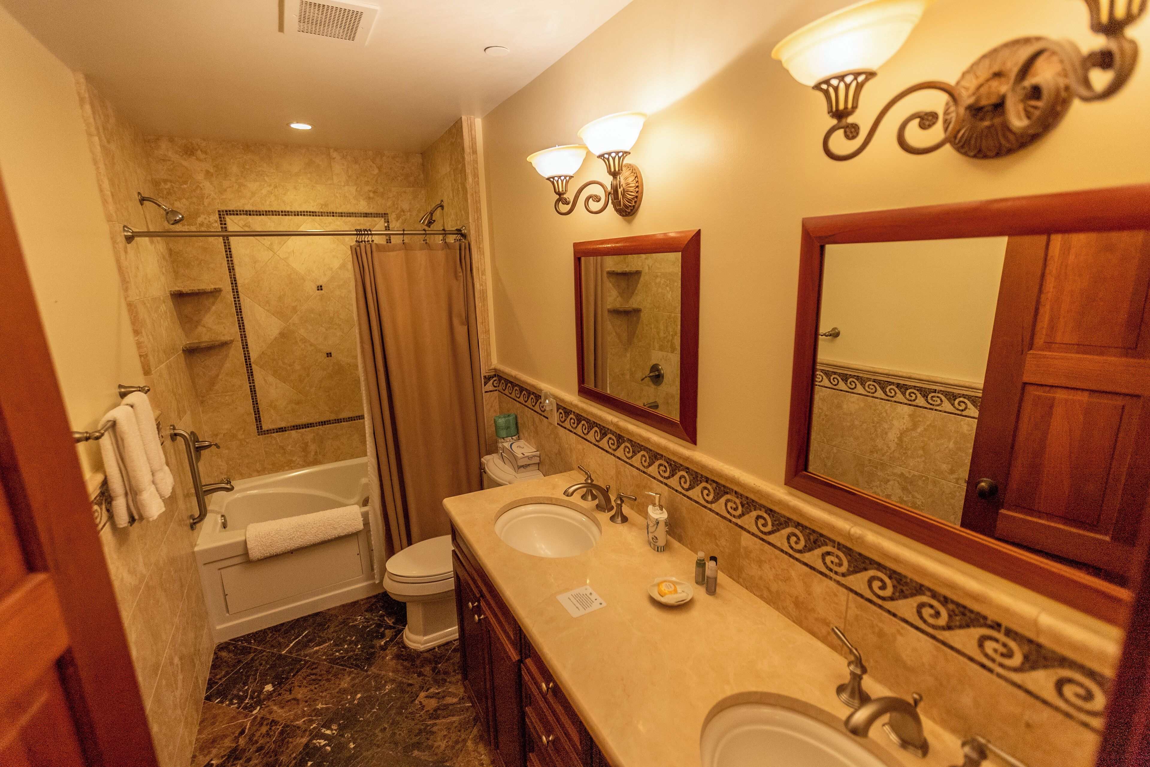 A bathroom with a bathtub, two sinks, a toilet, and a shower.