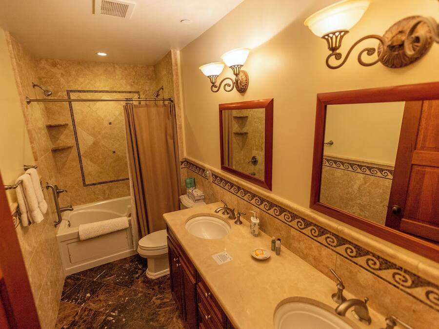 Un baño con bañera, dos lavamanos, inodoro y ducha.