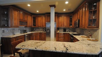 A kitchen with wooden cabinets, granite countertops, and stainless steel appliances.