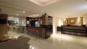 A modern hotel lobby with a reception desk, bar area, and dining space. - Hotel Klein Vllle Plus (Dois Irmaos)