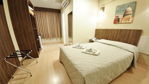 A hotel room with a bed, a bedside table, a lamp, a wall-mounted painting, and a window with curtains. - Hotel Klein Vllle Plus (Dois Irmaos)