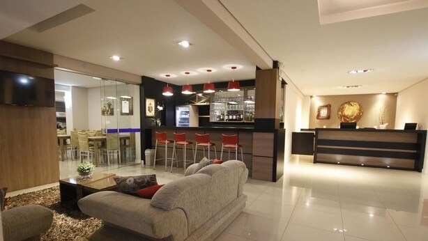 A modern hotel lobby with a seating area, a bar, and a reception desk. - Hotel Klein Vllle Plus (Dois Irmaos)