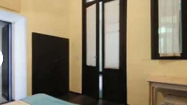 Um quarto com uma cama, uma porta e uma janela.