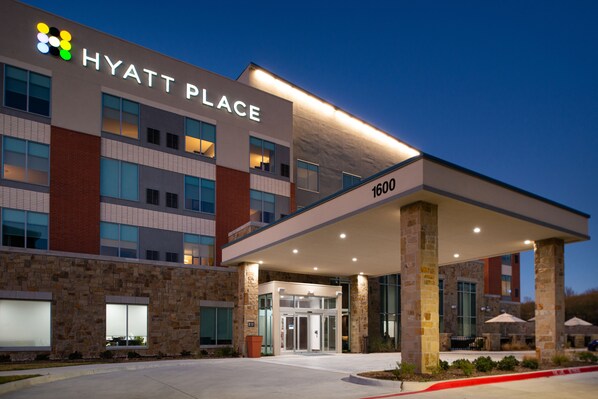 A Hyatt Place hotel with a modern design, featuring a stone facade, large windows, and a covered entrance area. - Hyatt Place Dallas/Rockwall (Rockwall)
