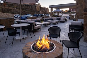 An outdoor patio area with stone flooring, round tables, and black wicker chairs. - Hyatt Place Dallas/Rockwall (Rockwall)