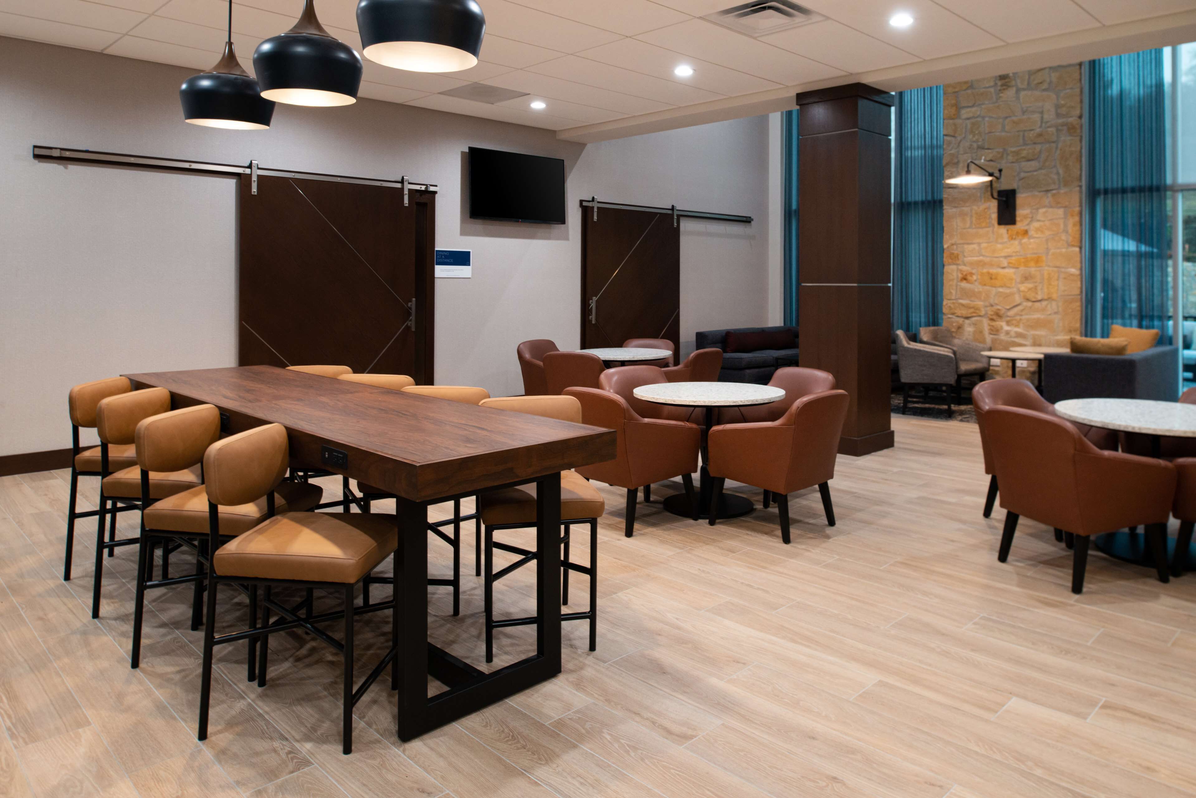 A conference room with a large wooden table, multiple chairs, and a television on the wall.