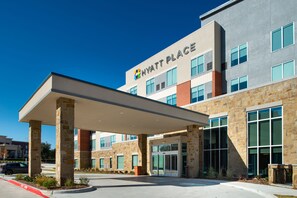 A modern hotel with a covered entrance, stone facade, and a clear blue sky. - Hyatt Place Dallas/Rockwall (Rockwall)