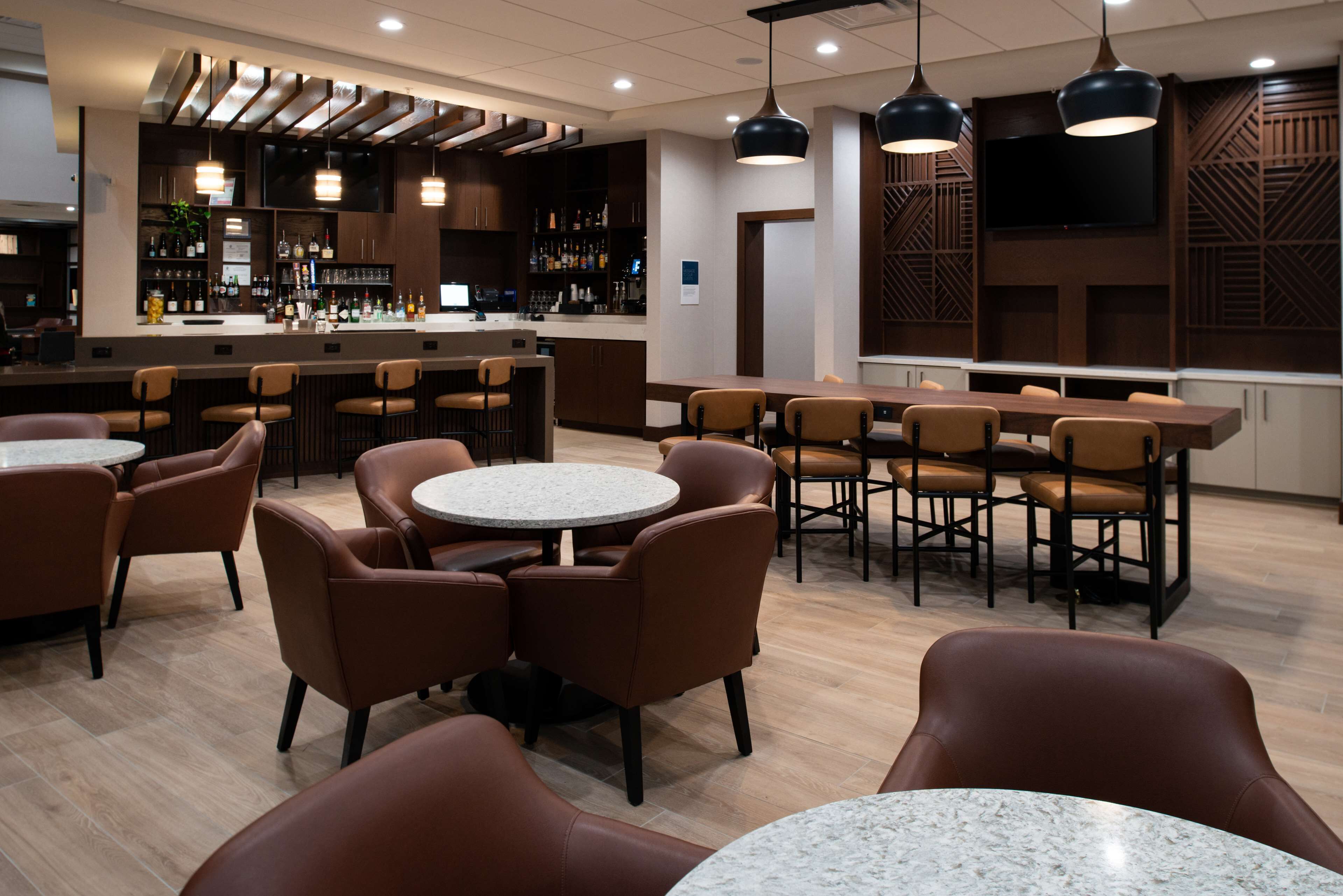 A modern bar area with a bar counter, seating, and a television screen.
