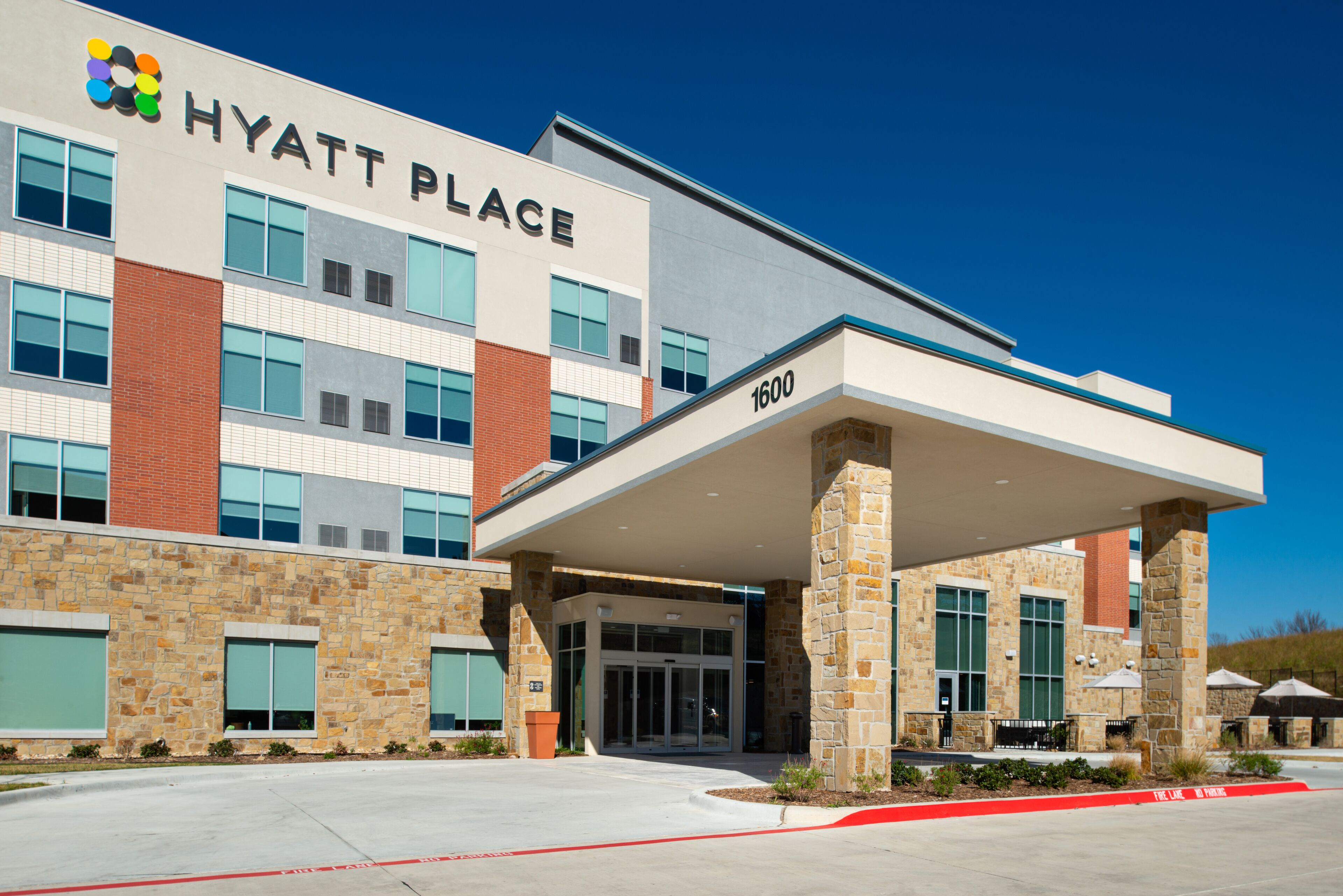 A modern hotel with a stone facade, large windows, and a covered entrance.