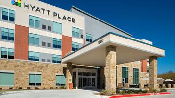 A modern hotel with a stone facade, large windows, and a covered entrance.