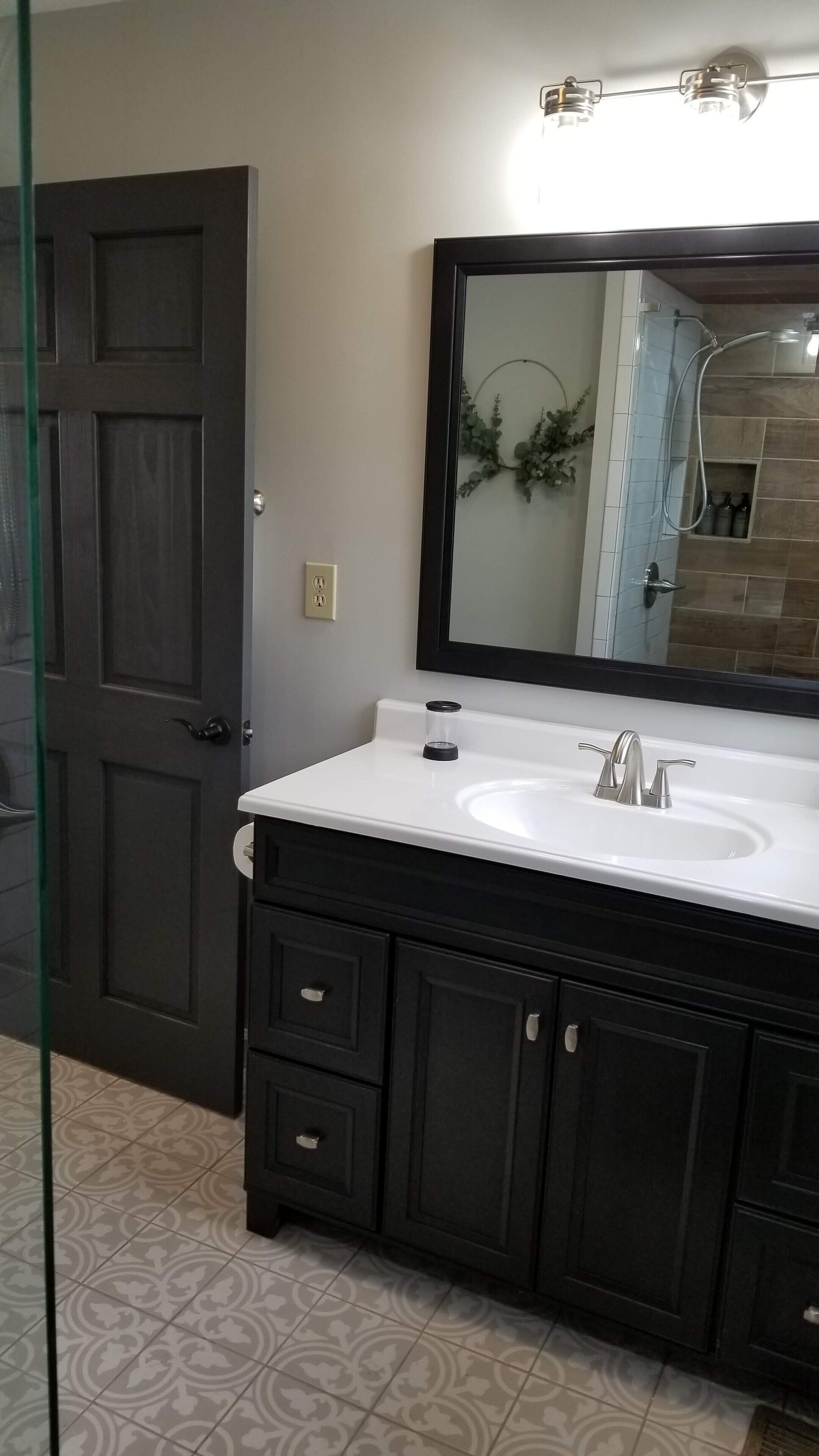 Un baño con tocador de madera oscura, lavamanos blanco y un espejo grande.
