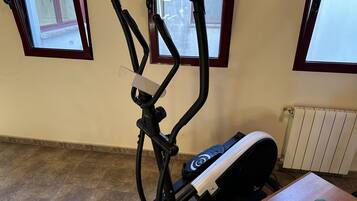 Een fitnessapparaat in een ruimte met betegelde vloer, een radiator en een raam met uitzicht.