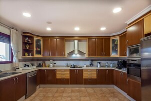 Una cocina moderna con armarios de madera, electrodomésticos de acero inoxidable y una campana extractora central.
