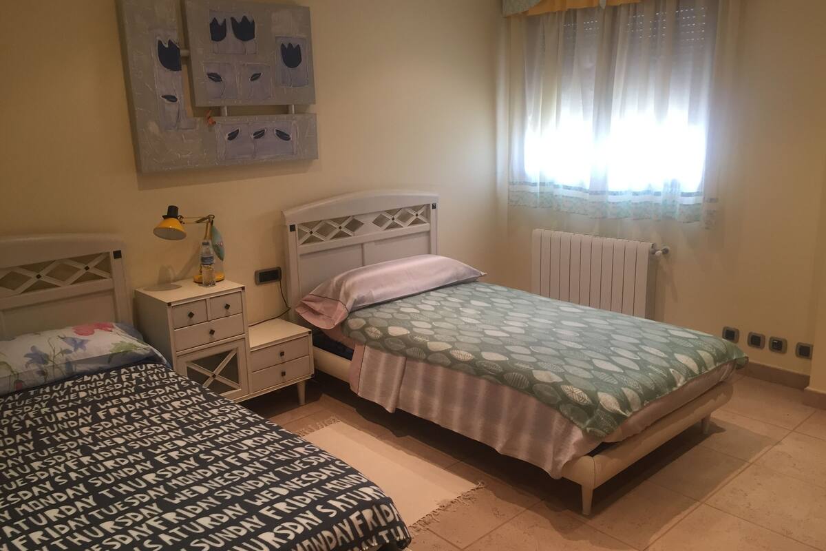 A bedroom with a bed, bedside tables, a lamp, and a radiator.