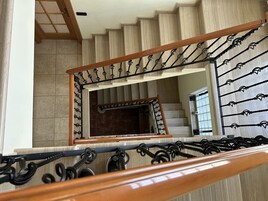 Una escalera de madera con barandillas de metal negro y pasamanos de madera.