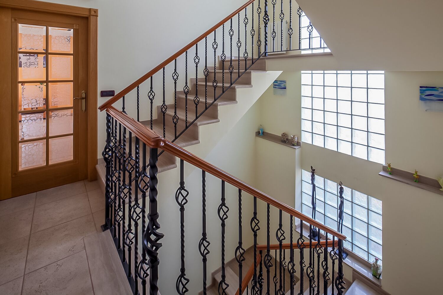 A staircase with a wooden handrail and black balusters, leading to an upper floor.