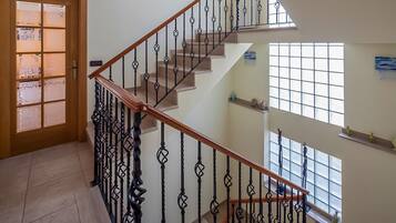 A staircase with a wooden handrail and black balusters, leading to an upper floor.