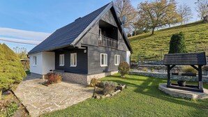 Une maison à deux étages, avec une façade sombre, des éléments de décoration blancs et un toit en pente.