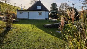 Une maison avec un toit en pente, un petit porche et une pelouse bien entretenue.