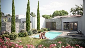Un área de piscina moderna al aire libre con un muro de piedra, árboles altos y un edificio con paredes de vidrio.