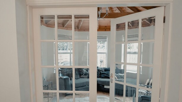 A room with a large white door leading to a living area with a couch and a rug. - Holiday Home Epworth (Doncaster)