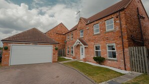 A two-story brick house with a white garage door, a small front yard, and a wooden fence. - Holiday Home Epworth (Doncaster)