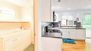 A modern kitchen with white cabinetry, a black stove, and a window overlooking a balcony. - Discount ! A mile to Narragansett beach & Boon Street Market this home has it all ! (Narragansett)