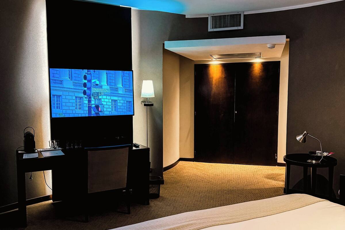 Ein Hotelzimmer mit Bett, Schreibtisch, Fernseher, Lampe und Schrank.