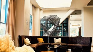 Una sala de estar moderna con un sofá modular, una mesa de centro redonda y una gran escultura abstracta.