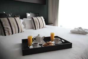 A neatly made bed with a tray of breakfast items including croissants, coffee, and orange juice. - Los Silos Hotel (Santa Fe)