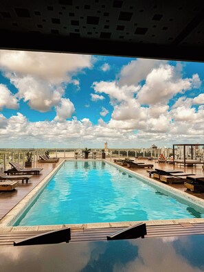 A rooftop pool with wooden loungers and a city view. - Los Silos Hotel (Santa Fe)