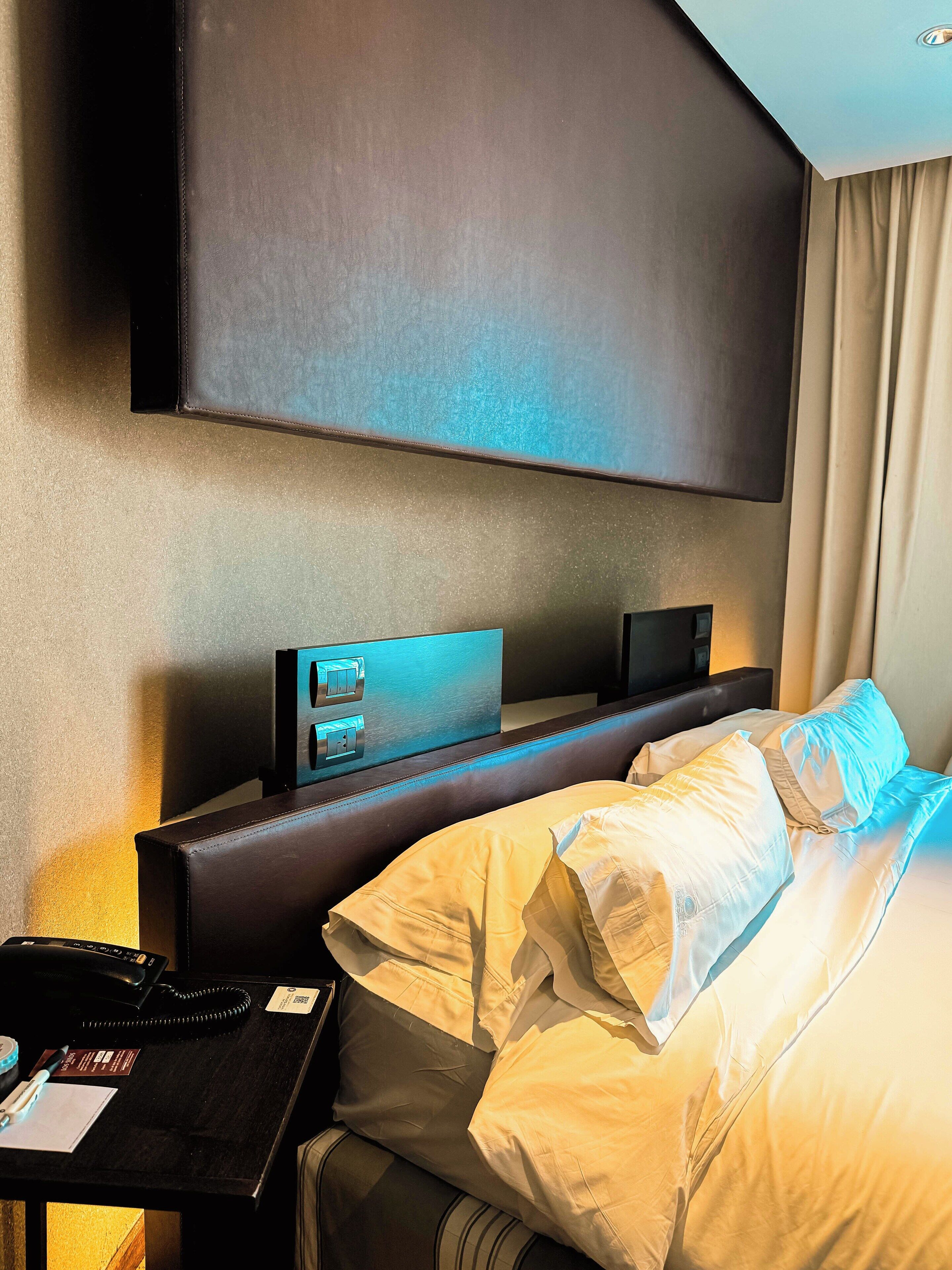 Habitación de hotel con una cama grande, un escritorio con teléfono y un televisor de pantalla plana en la pared.