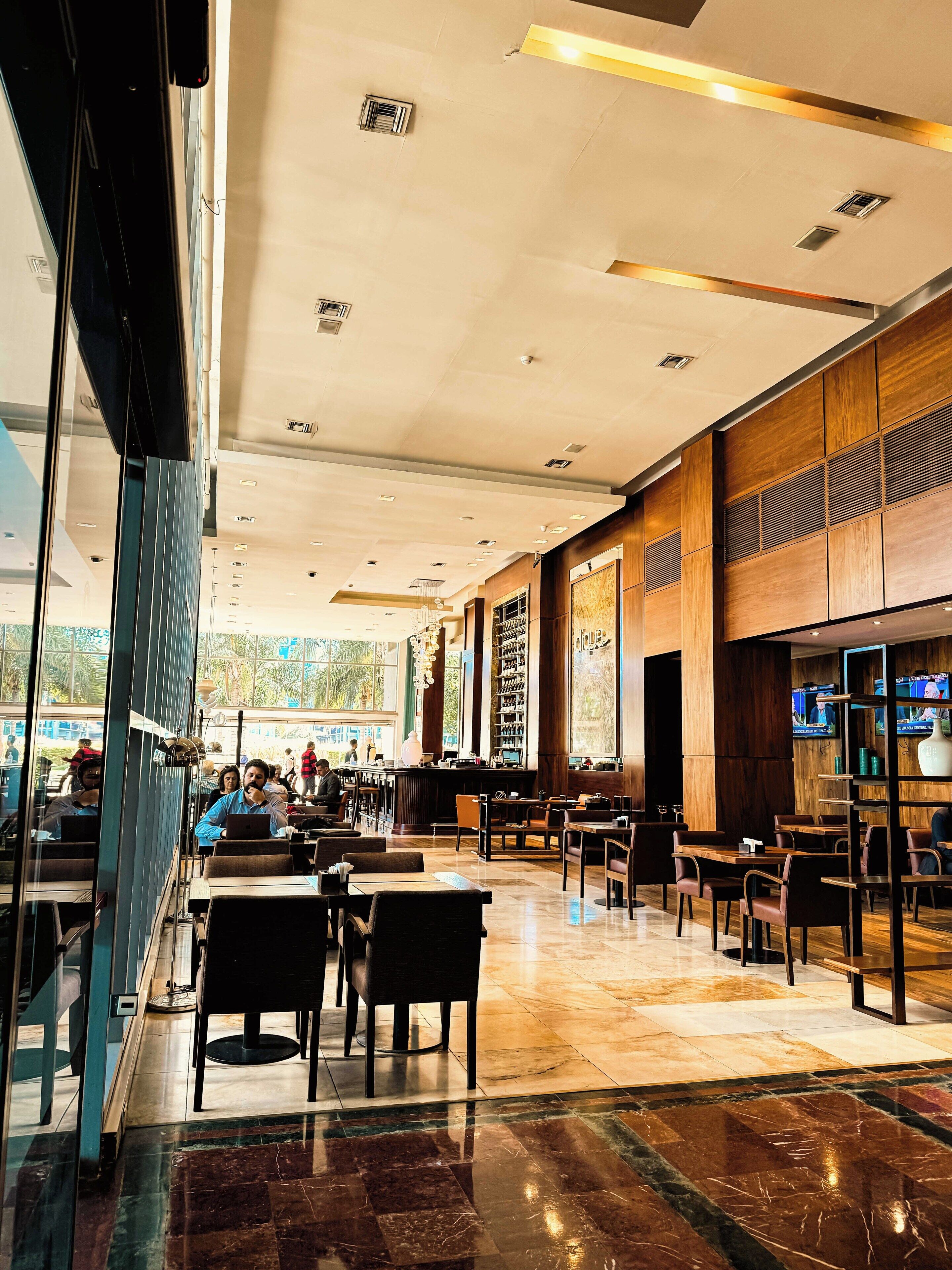A spacious restaurant with high ceilings, modern lighting, and a mix of seating arrangements.