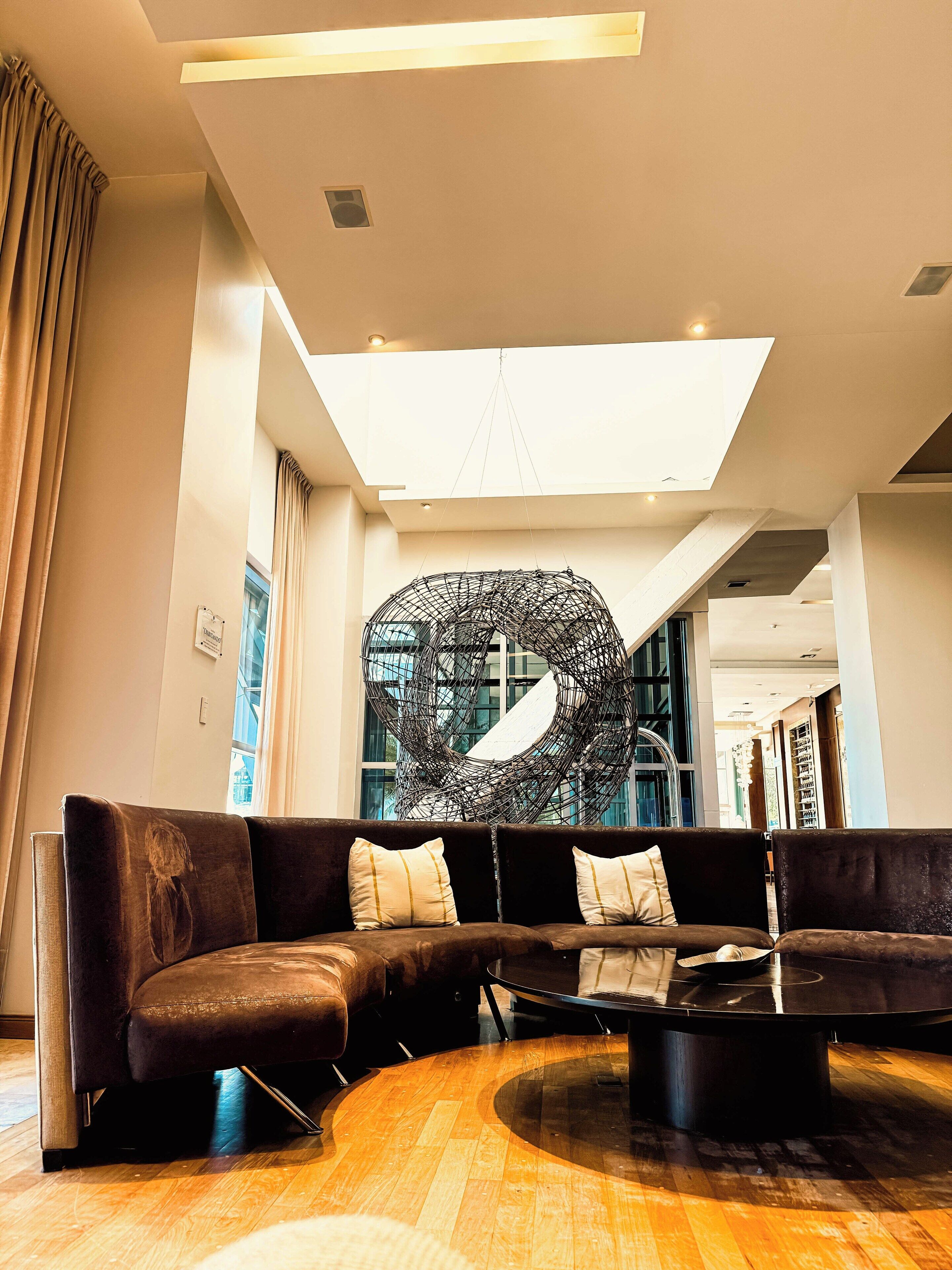 A modern lobby with a curved sofa, a round coffee table, and a unique abstract sculpture.